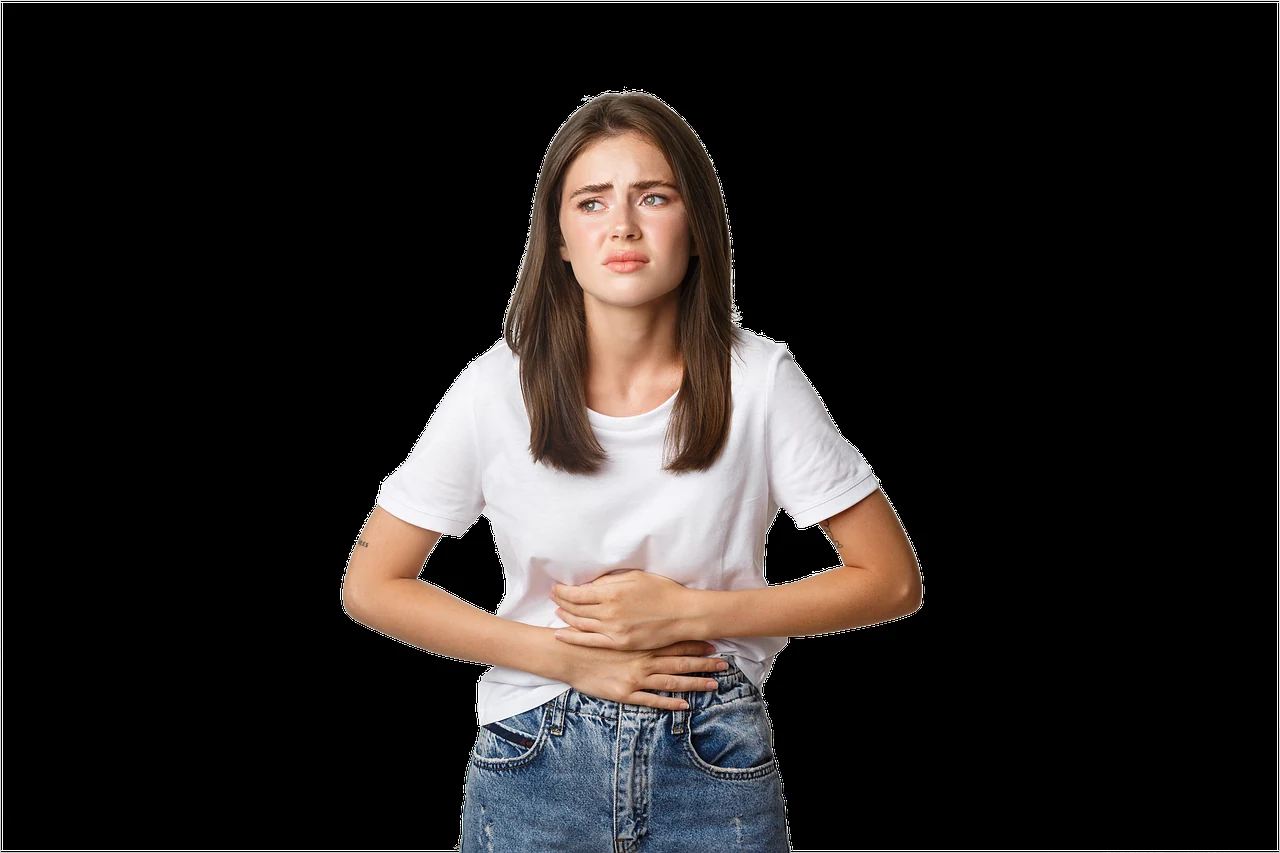 Young woman in a white T-shirt wincing and holding her stomach, a possible sign of gastritis