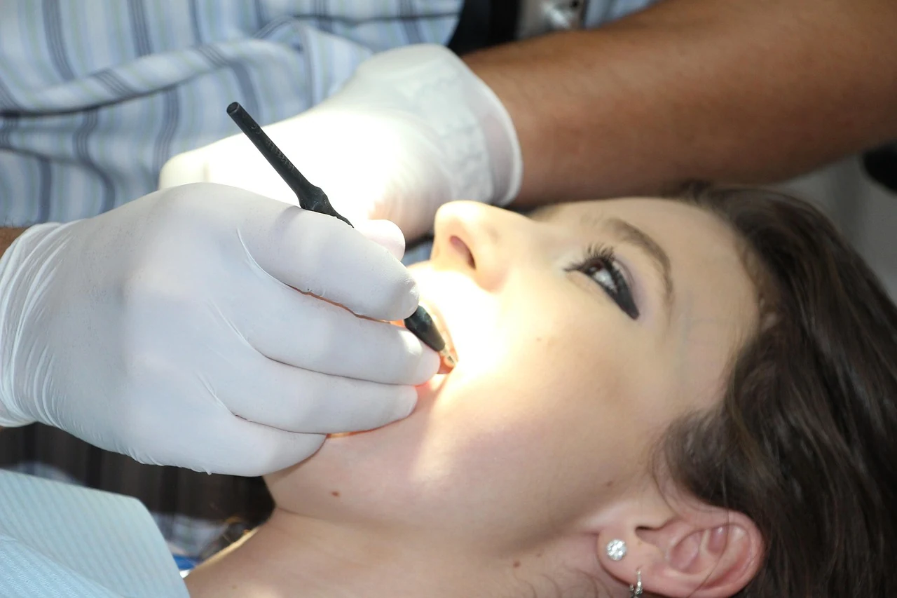 Dentist in gloves examines a patient's teeth and gums with an instrument for bleeding gums