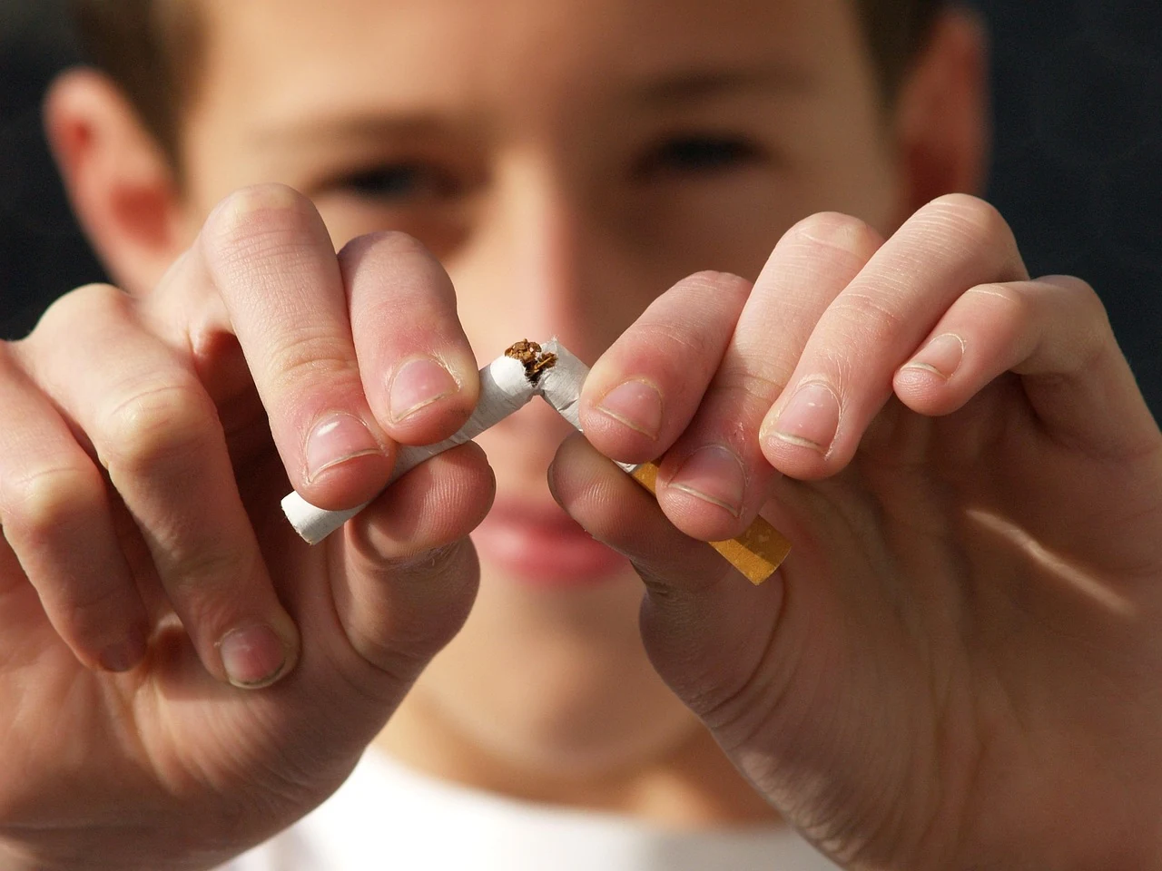 Young person snaps a cigarette in two with both hands, showing the decision to quit smoking for lung health