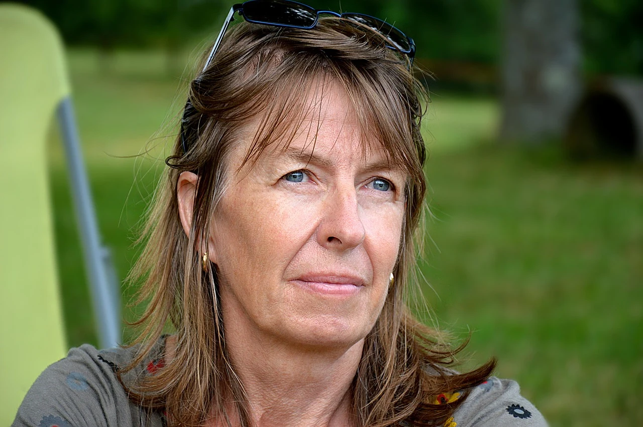 Middle-aged woman with sunglasses in her hair gazes thoughtfully into the distance, thinking about menopause