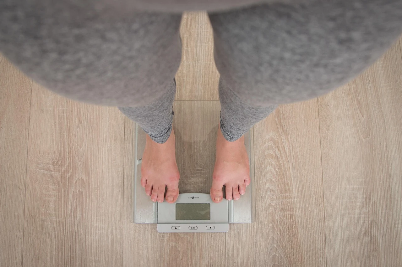 Barefoot woman standing on a bathroom scale to check her weight and metabolism