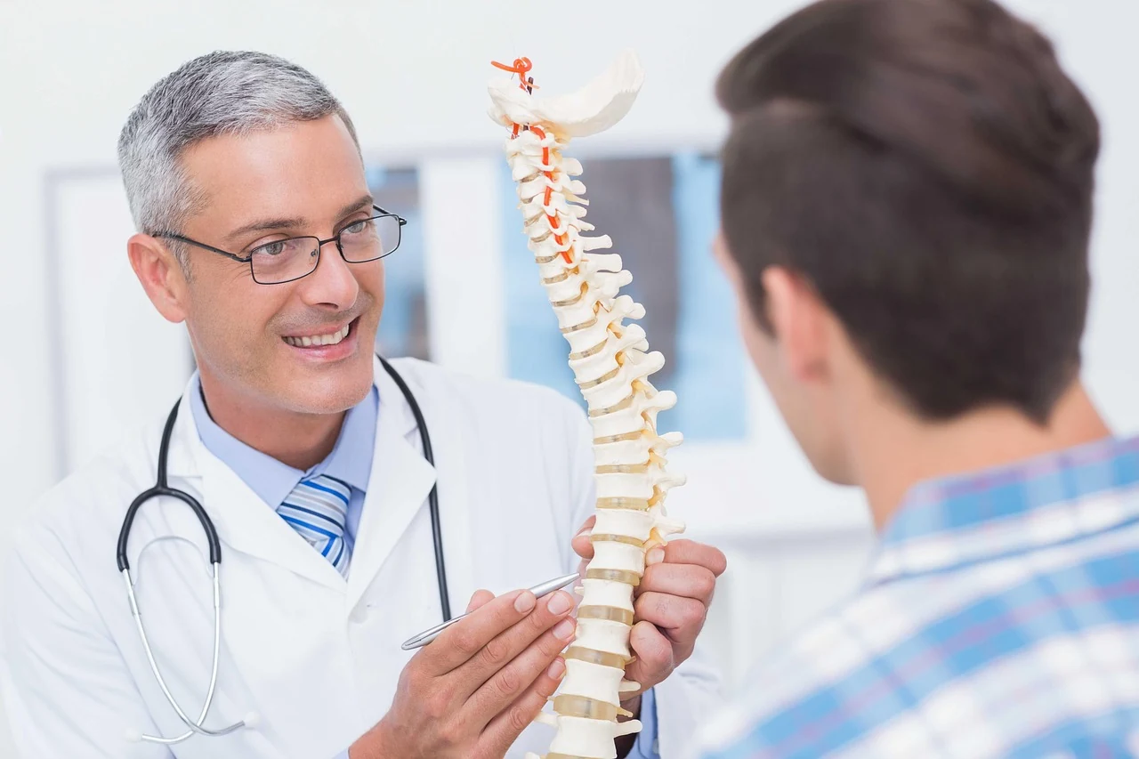Smiling doctor shows a patient a model of the spine, explaining why bones become fragile in osteoporosis