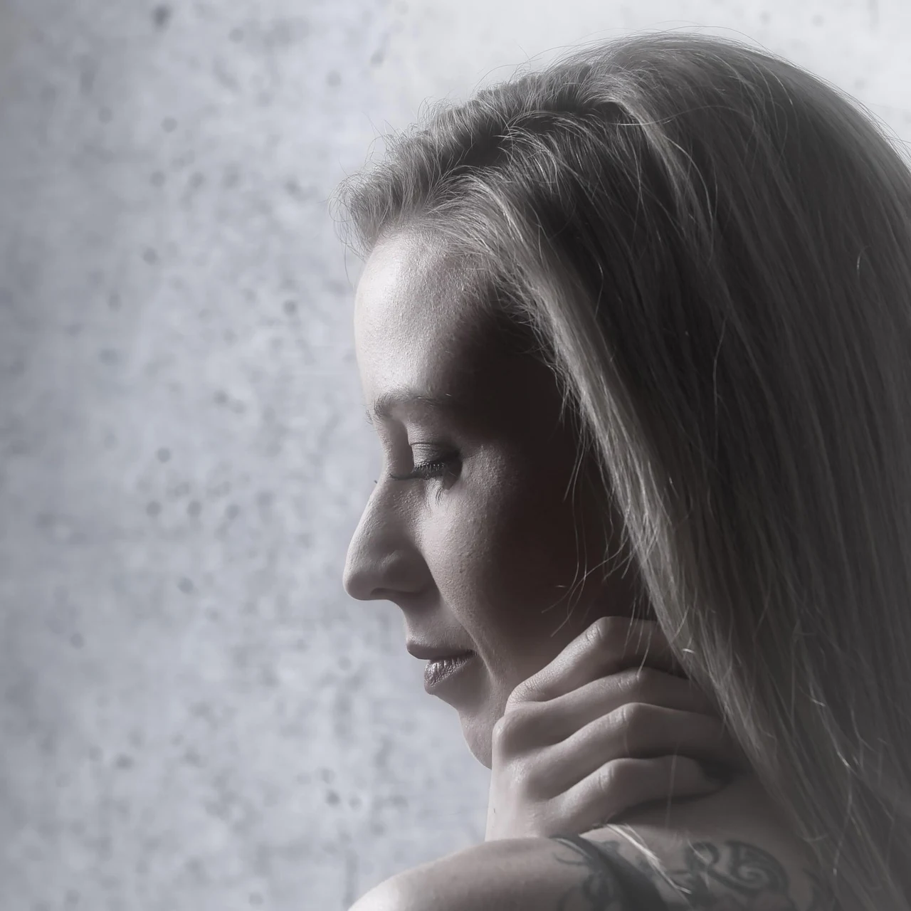 Woman in profile looks down with her hand against her neck, where the thyroid gland sits