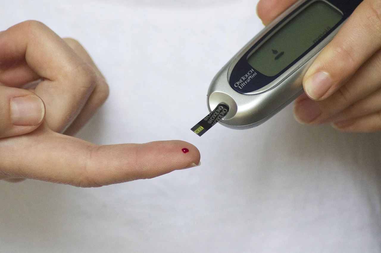 Drop of blood on a fingertip and a glucose meter with a test strip for checking blood sugar in endocrinology