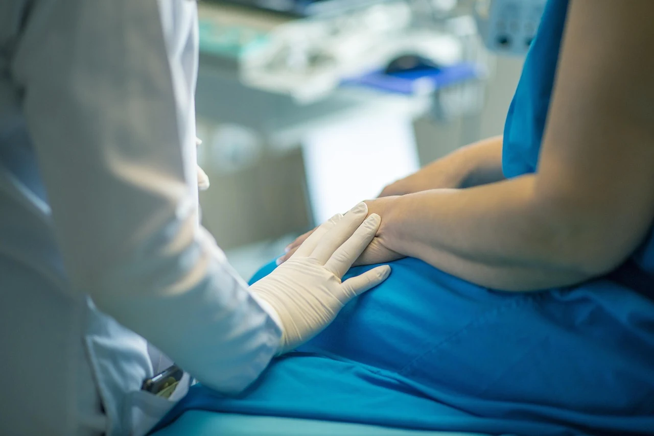Doctor in a medical glove touches the hand of a patient in blue clothing at a gynecology appointment